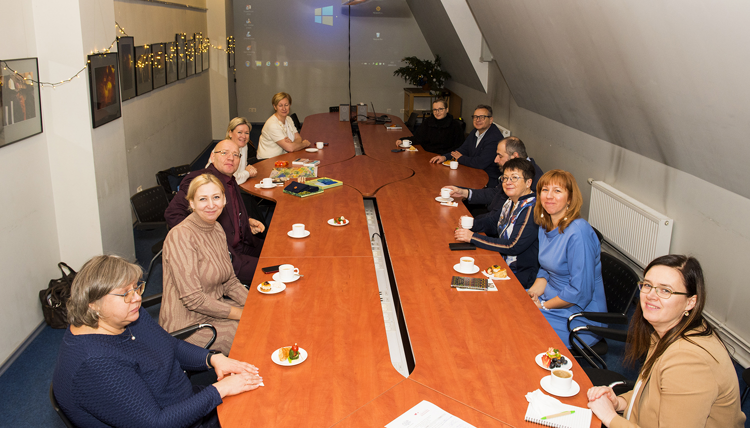 Valsts kancelejas darbinieki sēž pie galda muzeja konferenču zālē